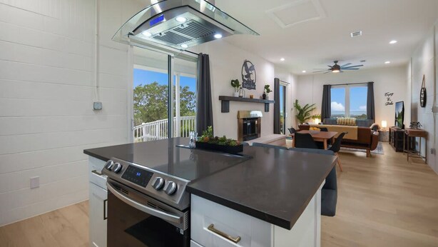 A modern kitchen with a central island, a dining area with a view, and a living room with a fireplace.