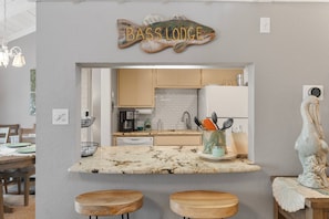 Una cocina con mostrador, taburetes de madera y un cartel con forma de pez.