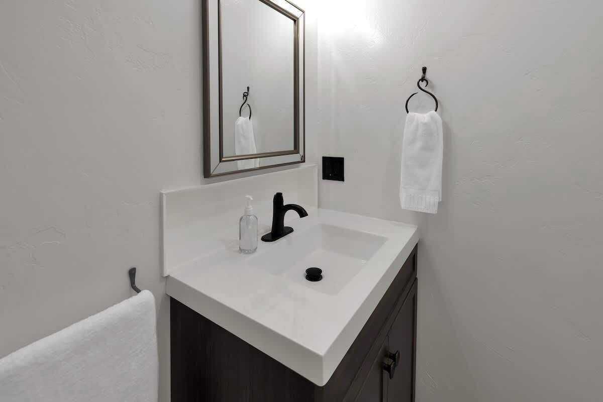 A bathroom with a white sink, a mirror, and a towel rack.