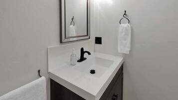 A bathroom with a white sink, a mirror, and a towel rack.