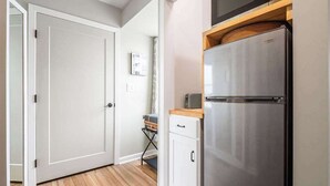 A compact kitchen with a stainless steel refrigerator, a microwave, and a small wooden countertop.