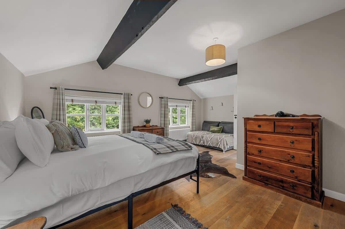A bedroom with a bed, a dresser, a mirror, and a window.