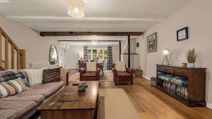 Ein geräumiges Wohnzimmer mit Couch, Ledersesseln, einem Holztisch und einem Bücherregal.