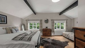 Ein Schlafzimmer mit Bett, Schminktisch, Spiegel und Fenster.