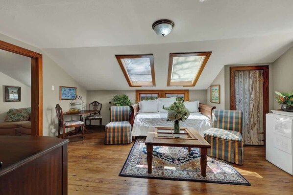 A loft-style bedroom with a bed, two skylights, a dining area, and a living room with a sofa and chairs. - West Suite in Gillespie House -steps to Main Street! (Fredericksburg)