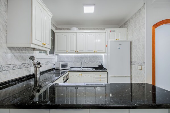 Een microgolfoven, een oven, een kookplaat, kookgerei, borden en bestek