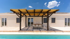 Une maison moderne dotée d’une piscine, d’un patio couvert et d’un coin repas.