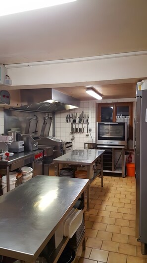 Una cocina comercial con electrodom ésticos de acero inoxidable, una mesa grande y un colgador para cuchillos.