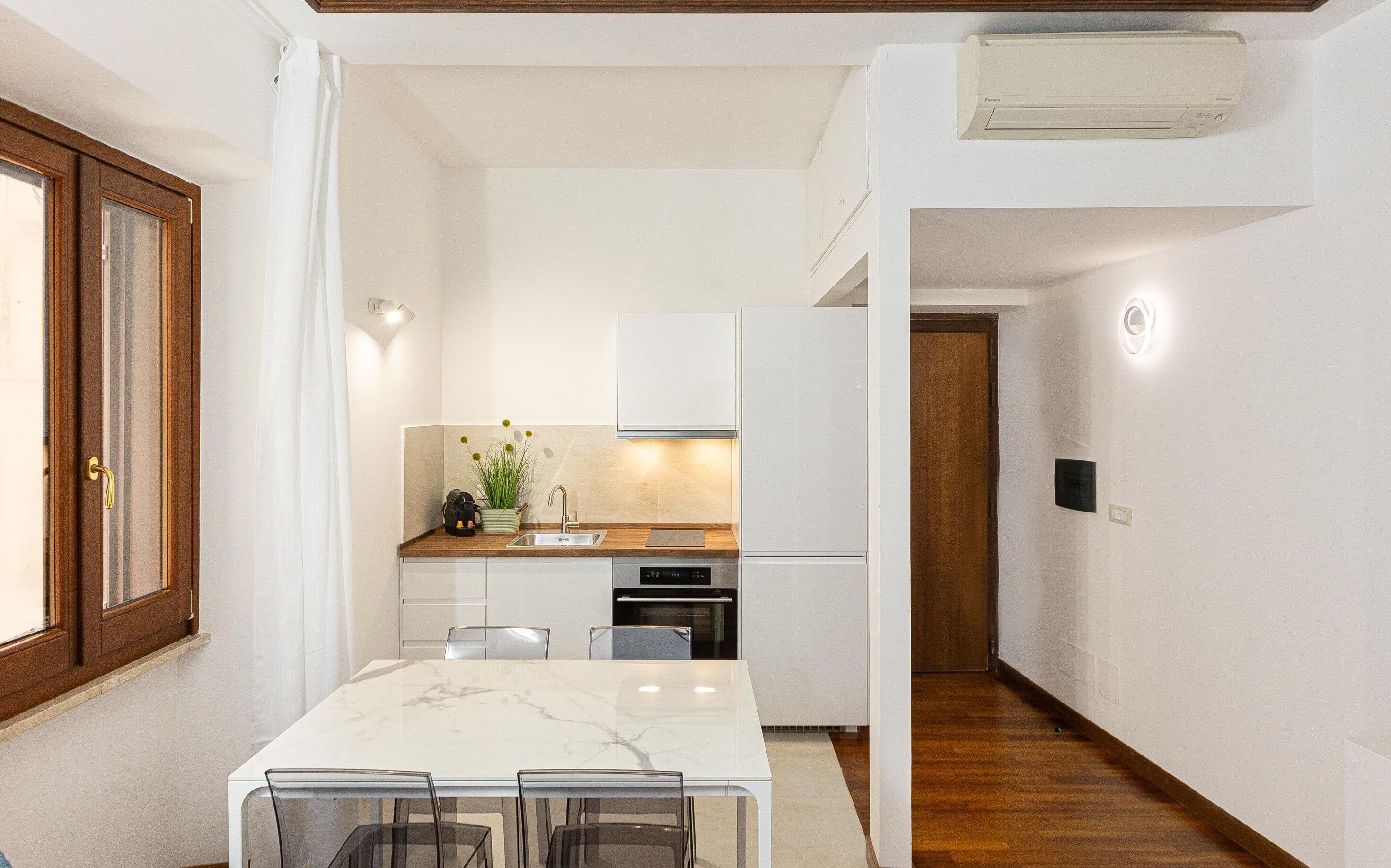 A compact kitchen with white cabinets, a built-in oven, and a refrigerator.