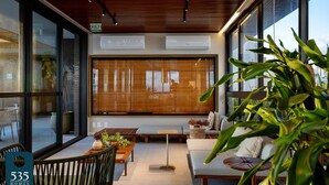 A modern interior with large windows, a wooden ceiling, and a seating area with a sofa and a table. - Unforgettable stay between Farol and Barra Mall (Salvador)
