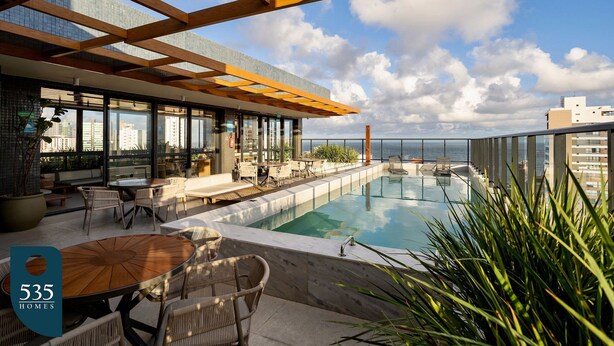 A rooftop pool area with outdoor seating and a view of the city skyline. - Unforgettable stay between Farol and Barra Mall (Salvador)