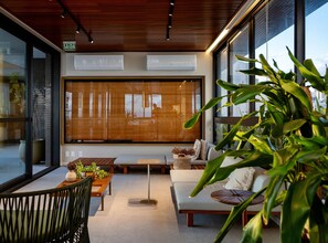 A modern interior with large windows, a wooden ceiling, and a seating area with a sofa and a table. - Unforgettable stay between Farol and Barra Mall (Salvador)