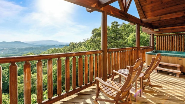 Une terrasse en bois offrant une vue sur les montagnes, des chaises en bois et un jacuzzi.