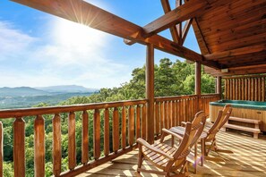 A wooden deck with a view of mountains, wooden chairs, and a hot tub. - Over the Moon (Sevierville)