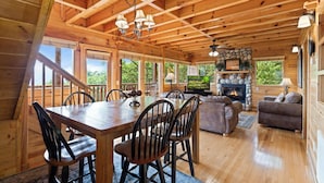 L’intérieur d’un chalet en bois comprend un coin repas, une cheminée et un espace de vie chaleureux.