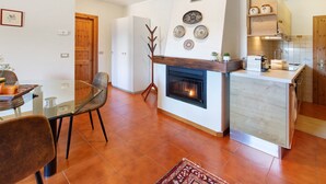Een moderne keuken met een open haard, een eethoek met een glazen tafel en een keukenblok.