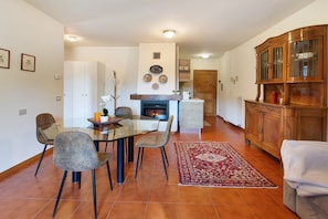 A dining area with a glass table, chairs, a fireplace, and a wooden cabinet.