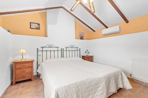 A bedroom with a bed, a nightstand with a lamp, a wooden headboard, and a radiator.