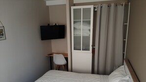 A bedroom with a bed, a desk, a chair, a television, and a wardrobe. - Apartment 102 - Cosy T2 60 m² (Bourg-Saint-Andéol)