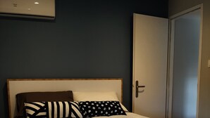Un lit avec un cadre en bois, une couette blanche et deux coussins à motifs.