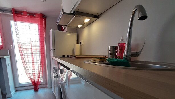 Une cuisine dotée d’un plan de travail en bois, d’un évier en acier inoxydable et d’un lave-linge.
