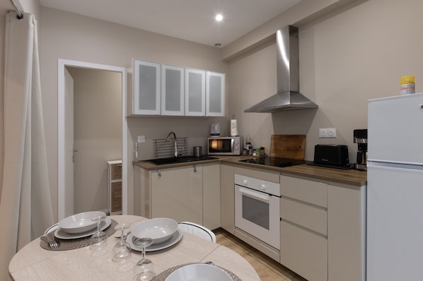 A kitchen with white cabinets, a microwave, a stove, and a refrigerator.