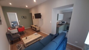 Un salon avec un canapé bleu, une table basse en bois et un coin repas avec une chaise rouge.