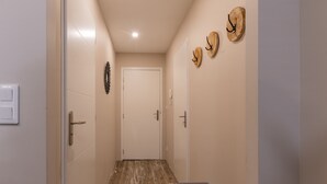 A narrow hallway with a wooden floor, a bench, and a door at the end.