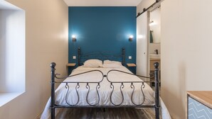 A bed with a metal frame, a blue accent wall, and a mirror above it.