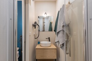 A bathroom with a white sink, a mirror, a towel rack, and a shower.