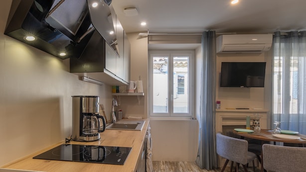 A modern kitchen with a built-in stove, a coffee maker, and a dining area with a table and chairs.