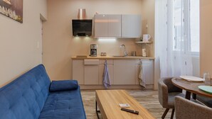 A compact living space with a kitchenette, a sofa, a dining table, and a window with curtains.