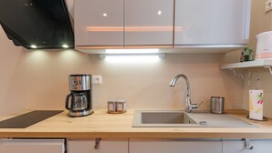 A modern kitchen with a coffee maker, a kettle, a sink, and a countertop.