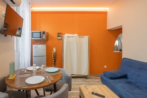 Un espace de vie compact comprenant un coin repas, une kitchenette et un canapé bleu.