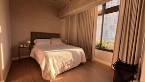 A bedroom with a bed, bedside tables, a window with curtains, and a view of buildings outside. - Guatemala cozy,centric apartment in Zona 4 (Ciudad de Guatemala)