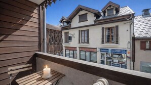 A balcony with a candle, wooden bench, and a view of buildings.