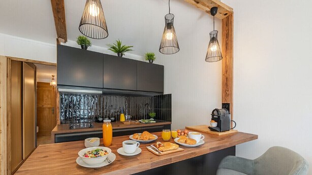 A modern kitchen with a wooden island, black cabinets, and pendant lighting.