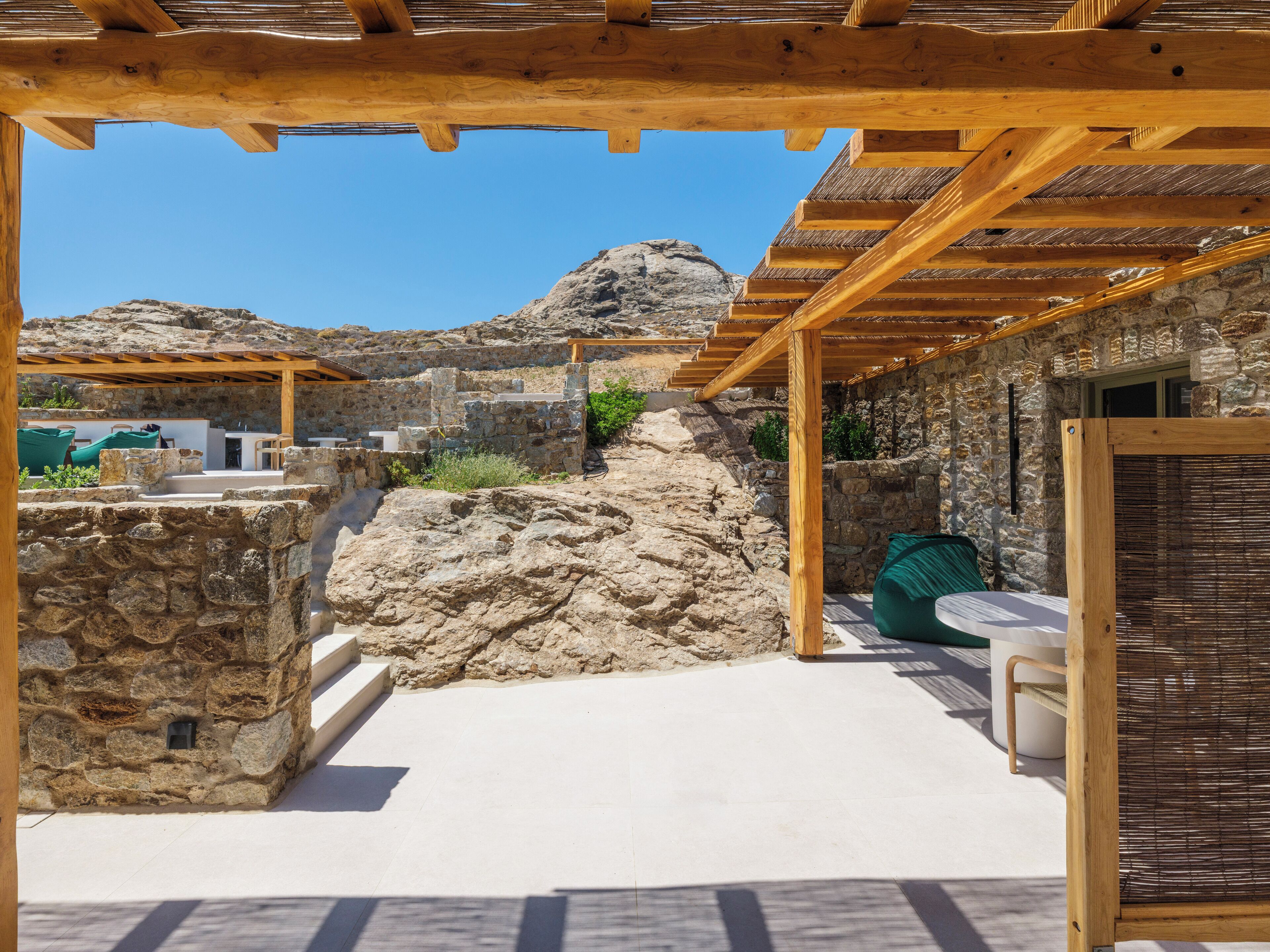 A stone building with a wooden pergola and outdoor seating area.