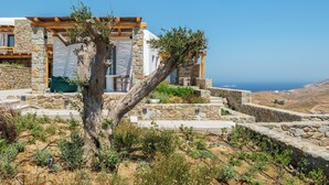 A stone building with a wooden pergola and a view of the sea. - Mykonian Shades (Ano Mera)
