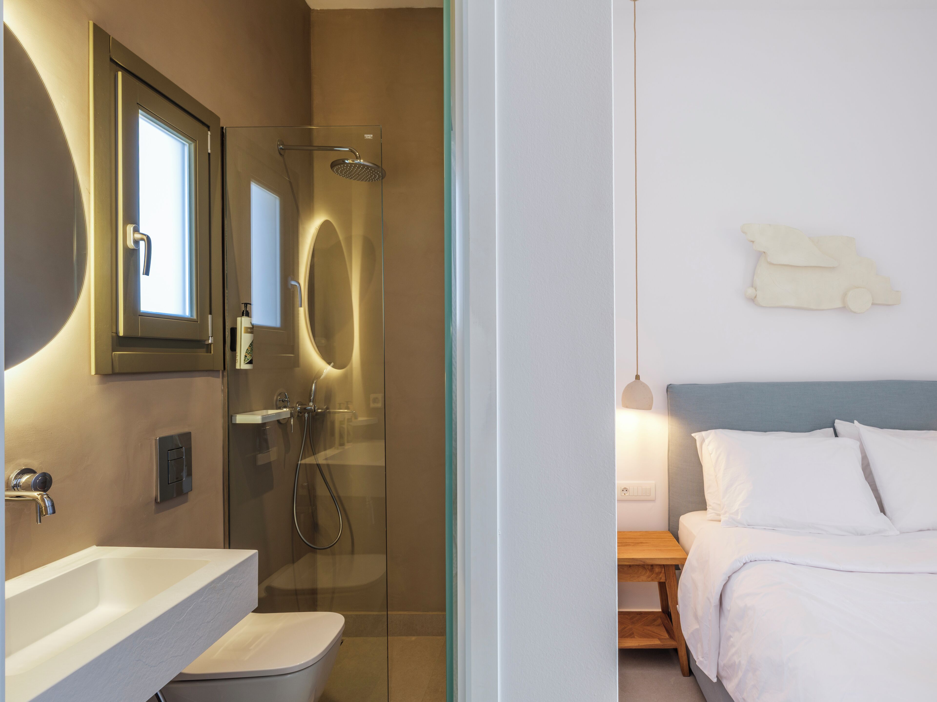 Un baño moderno con ducha de vidrio, lavamanos blanco y espejo.