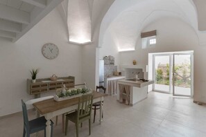 Una cocina amplia con comedor, un reloj en la pared y vistas a través de la puerta de cristal.
