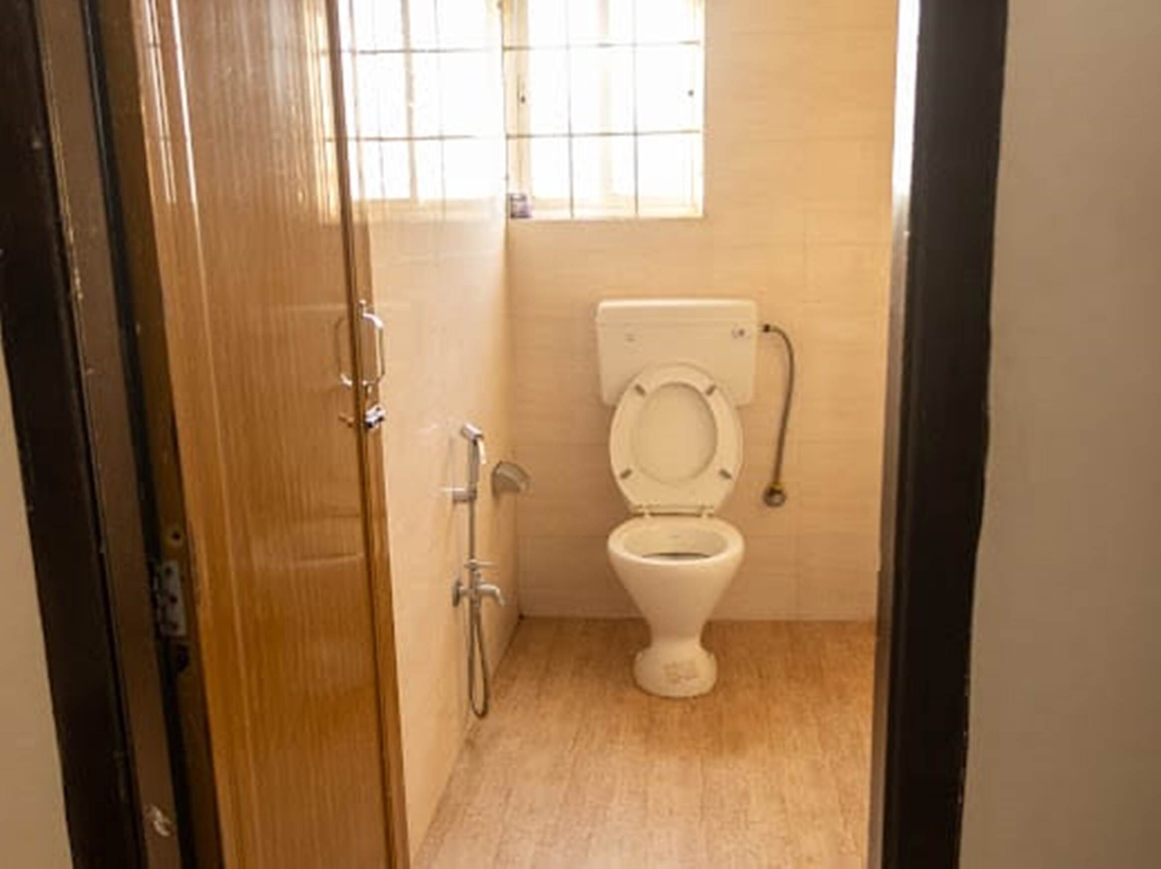 A small bathroom with a toilet, a shower, and a window.