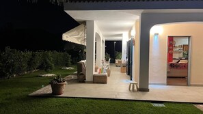 Een modern terras buiten met zitplaatsen, een overdekt gedeelte en uitzicht op het huis.