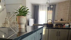 Una cucina moderna con un piano di lavoro in marmo, elettrodomestici in acciaio inox e una pianta in vaso.
