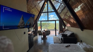 Ein Zimmer mit großem Fenster, einem Bett, einer Couch und einem Fernseher.