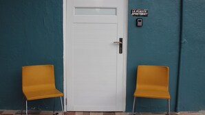 A white door with a glass panel, two yellow chairs, and a sign reading "LA PLACITA APARTMENT".
