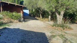 Un camino de grava que lleva a un edificio con muro de piedra y porche cubierto.