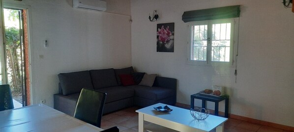 A living room with a sofa, a small table, and a window with a view.