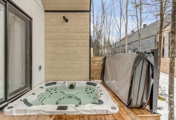 Ein Whirlpool auf einer Holzterrasse mit einem überdachten Bereich zur Rechten.