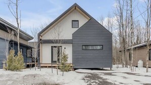 A modern two-story house with a large front porch, a garage, and a small attached shed.